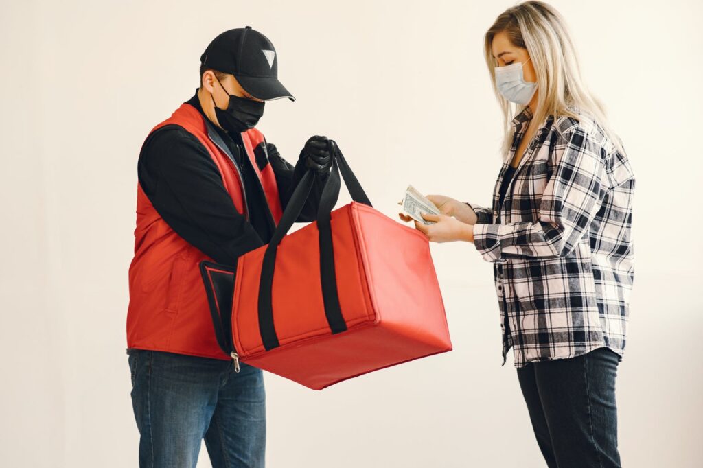 Delivery agent handing over the parcel of food to the customer with safety.